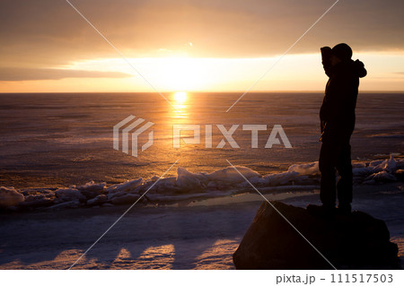 Man on rock on the sea in the ice - silhouette 111517503