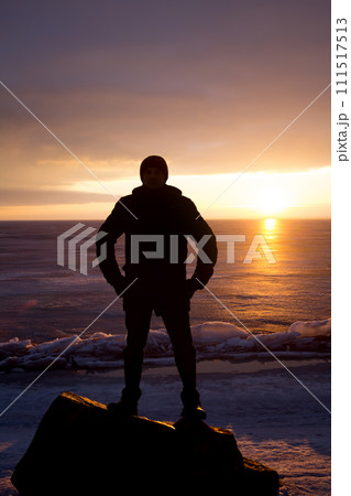 Man on rock on the sea in the ice - silhouette 111517513