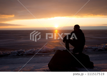 Man on rock on the sea in the ice - silhouette 111517519
