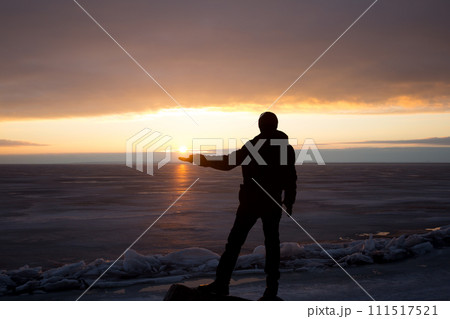 Man on rock on the sea in the ice - silhouette 111517521