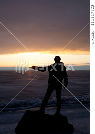 Man on rock on the sea in the ice - silhouette 111517522