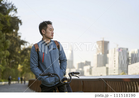 young asian man sitting on his bike lost in thought young asian man sitting on his bike lost in thought 111518190