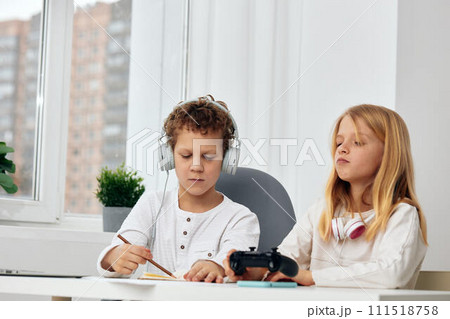 Happy Siblings Taking a Selfie Two teenagers, a boy and a girl, seated indoors, are captured in a moment of playful bonding With beaming smiles and smartphones in hand, they are engrossed in the joy 111518758