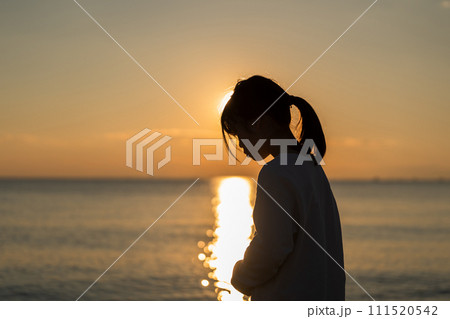 夕焼けの中、海辺に立つ女の子。 夕焼けの中、海辺に立つ女の子。 111520542