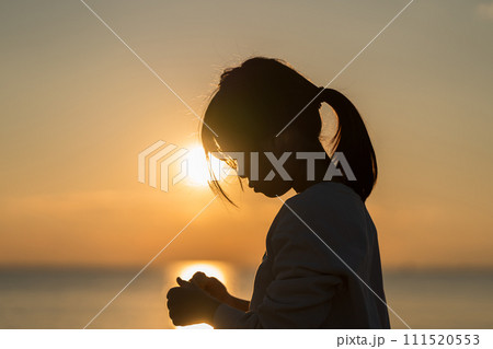 夕焼けの中、海辺に立つ女の子。 111520553