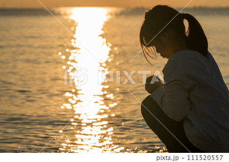 夕焼けの中、海辺に立つ女の子。 111520557