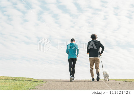 青空の見える公園で犬の散歩・運動・トレーニング・有酸素運動をするさわやかな家族・親子 青空の見える公園で犬の散歩・運動・トレーニング・有酸素運動をするさわやかな家族・親子 111521428