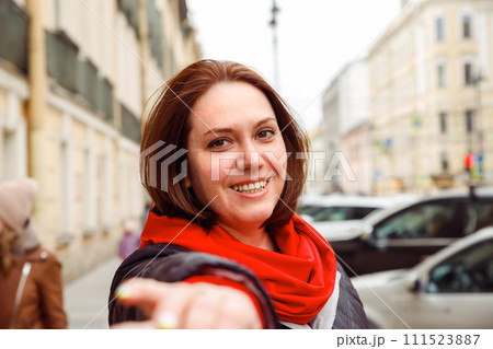 smiling brunette young Caucasian female woman pulling hand in camera on street of european city. follow me, date, love, valentine's day concept. lifestyle portrait 111523887