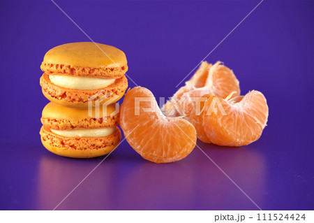 Stack of orange macaroons next to a peeled tangerine 111524424