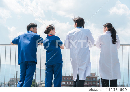 病院の屋上で休憩時間を過ごす男女の医師・医者・看護師・医療従事者・技師の後ろ姿（4人） 111524690