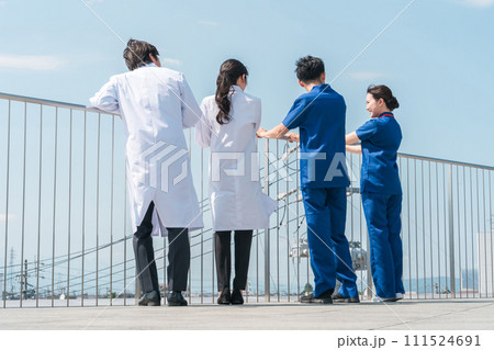 病院の屋上で休憩時間を過ごす男女の医師・医者・看護師・医療従事者・技師の後ろ姿（4人） 111524691