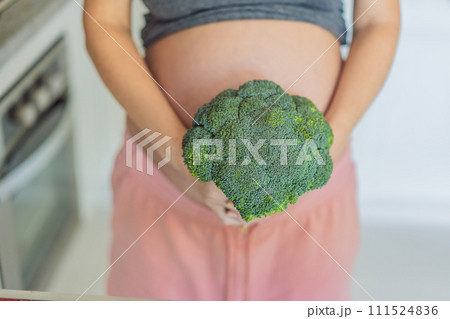 Embracing a nutrient-rich choice, a pregnant woman eagerly prepares to enjoy a wholesome serving of broccoli, prioritizing healthy and nourishing options during her pregnancy 111524836