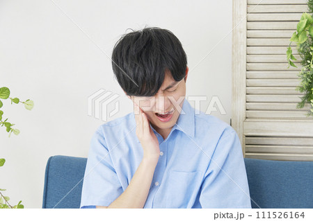 リビングで虫歯が痛む男性 111526164
