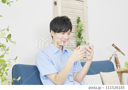 リビングでスマートフォンで動画を見る男性 111526185