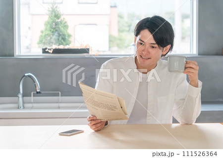 新聞を読みながらコーヒーを飲む若いアジア人男性 111526364