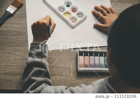 絵の具を使って白い紙に絵を描いている男の子 111528298