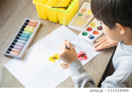 絵の具を使って白い紙に絵を描いている男の子 111528400
