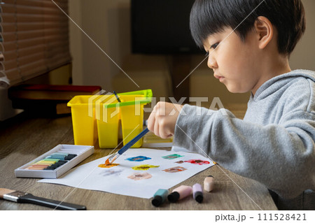 絵の具を使って白い紙に絵を描いている男の子 111528421