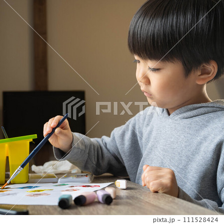 絵の具を使って白い紙に絵を描いている男の子 絵の具を使って白い紙に絵を描いている男の子 111528424