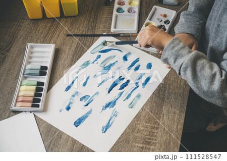 子どもが絵の具を使い白い紙に絵を描く様子 111528547