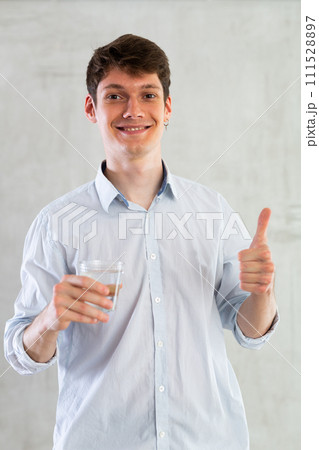 Young guy posing with glass of water in studio 111528897