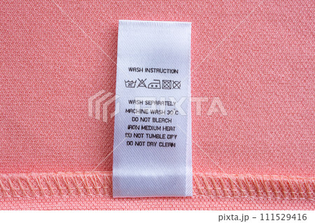 White laundry care washing instructions clothes label on pink cotton shirt 111529416