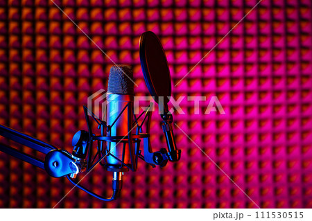 Professional studio microphone against acoustic foam panel background in neon light 111530515