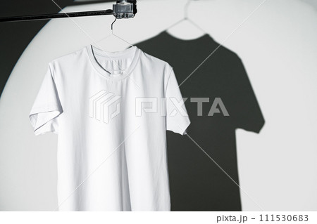 Blank T-shirt hanging in a spotlight in studio Blank T-shirt hanging in a spotlight in studio 111530683