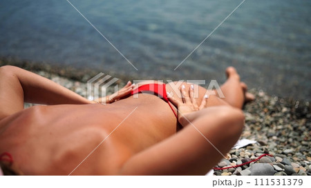 Woman taking red bikini off on beach for tan, lady stripping holiday swimsuit with bow in string. Fun and relax, sexy model untying swimming costume bra, happy woman in swimwear on vacation Woman taking red bikini off on beach for tan, lady stripping holiday swimsuit with bow in string. Fun and relax, sexy model untying swimming costume bra, happy woman in swimwear on vacation 111531379