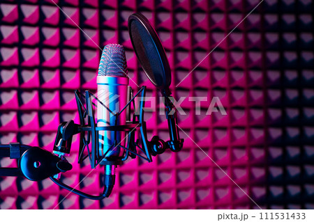 Professional studio microphone against acoustic foam panel background in neon light Professional studio microphone against acoustic foam panel background in neon light 111531433