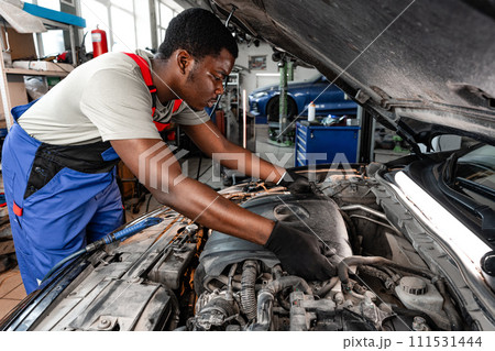Young African male mechanic repairs car in garage close up 111531444