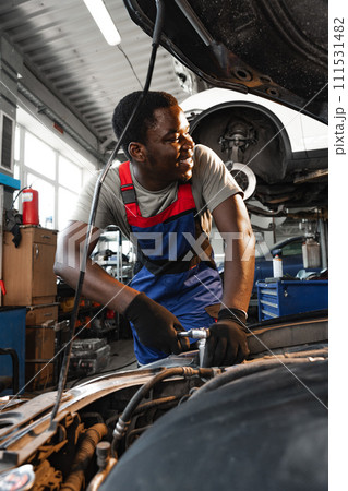 Young African male mechanic repairs car in garage close up Young African male mechanic repairs car in garage close up 111531482