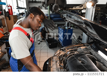 Young African male mechanic repairs car in garage close up Young African male mechanic repairs car in garage close up 111531721