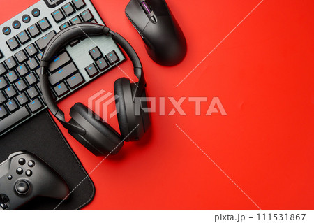 Computer keyboard and headphones on red background top view Computer keyboard and headphones on red background top view 111531867