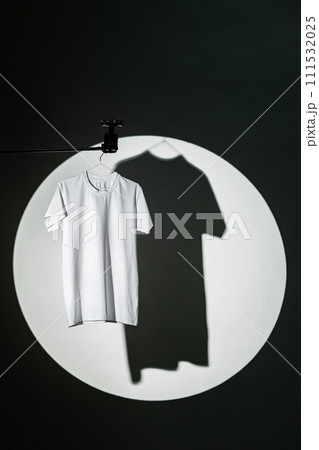 Blank T-shirt hanging in a spotlight in studio 111532025