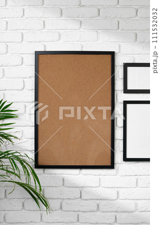 Black picture frame hanging on white brick wall copy space 111532032