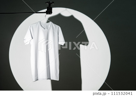 Blank T-shirt hanging in a spotlight in studio Blank T-shirt hanging in a spotlight in studio 111532041