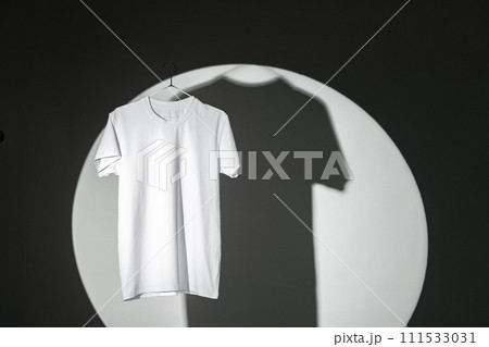 Blank T-shirt hanging in a spotlight in studio 111533031