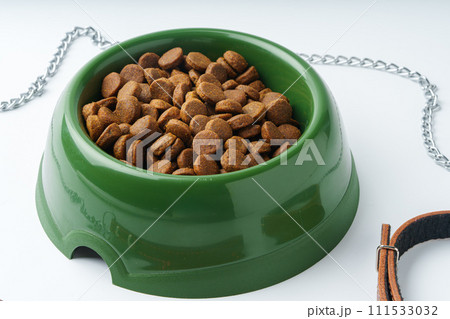 Green plastic bowl with dry pet food isolated on white Green plastic bowl with dry pet food isolated on white 111533032