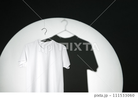 Blank T-shirt hanging in a spotlight in studio Blank T-shirt hanging in a spotlight in studio 111533060