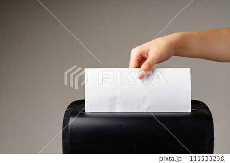 Hand using paper shredding machine against gray background 111533238