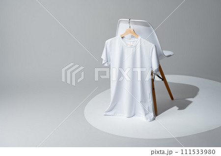 White blank t-shirt hanging on chair in empty room 111533980