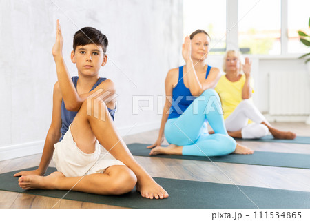 Mother, grandmother and adolescence son do exercise lord of fish, Ardha Matsyedrasana 111534865