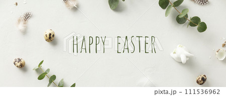 eucalyptus branches, eggs, feathers, ceramic bunny on light grey background 111536962