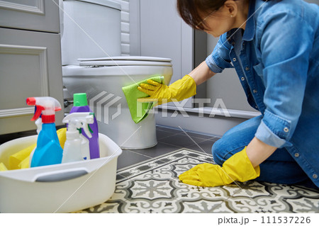 Woman in gloves using cleaning detergent clean toilet in bathroom 111537226