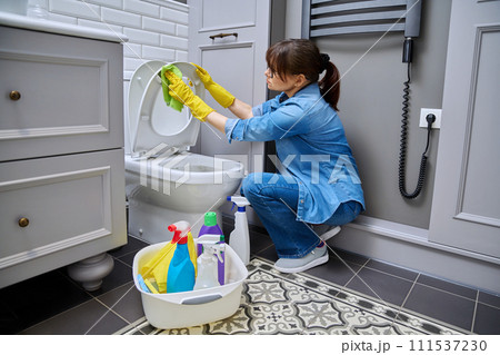 Woman in gloves using cleaning detergent clean toilet in bathroom Woman in gloves using cleaning detergent clean toilet in bathroom 111537230