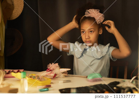 Portrait of young Black girl looking into mirror backstage preparing for theater performance copy space 111537777