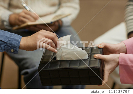 Close up of unrecognizable person taking tissue from box during emotional therapy session, copy space 111537797