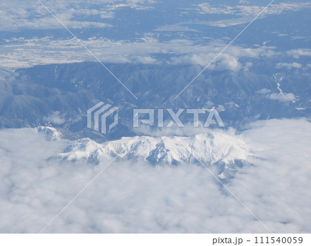 飛行機で雲の上から見た雪で白くなった山 飛行機で雲の上から見た雪で白くなった山 111540059
