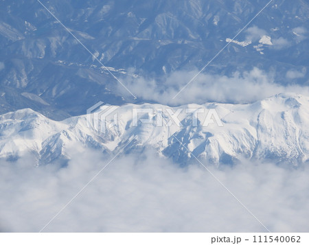 飛行機で雲の上から見た雪で白くなった山 飛行機で雲の上から見た雪で白くなった山 111540062